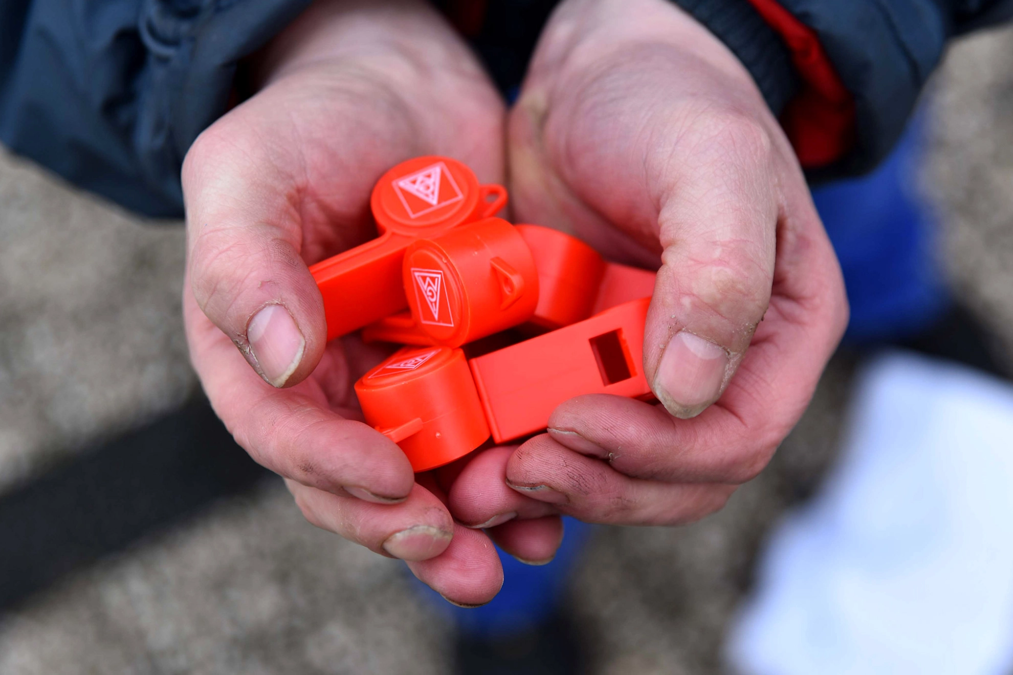 Hände halten rote Trillerpfeifen.