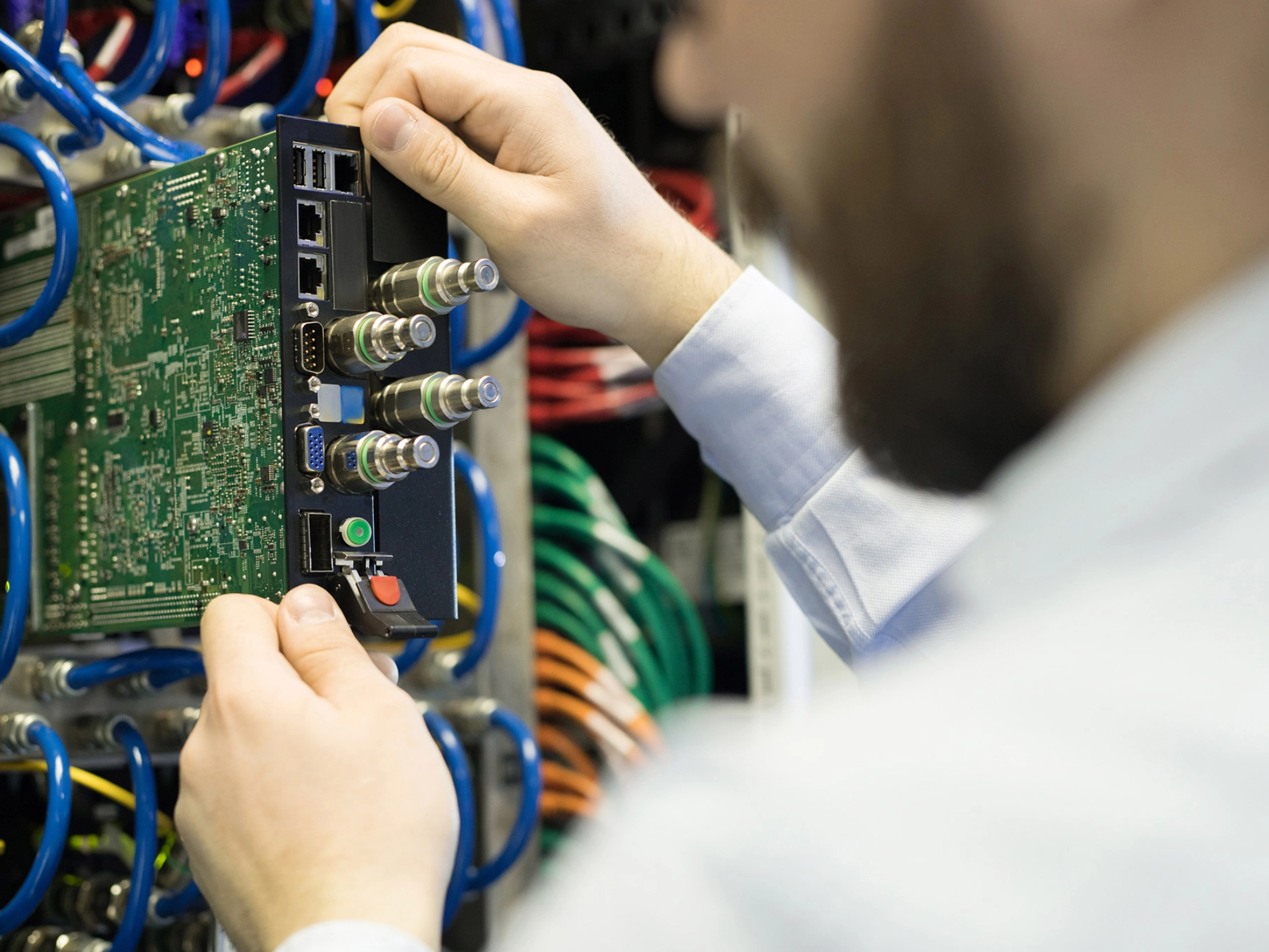 Ein Mann mit Bart zieht eine Komponente aus einem Server.